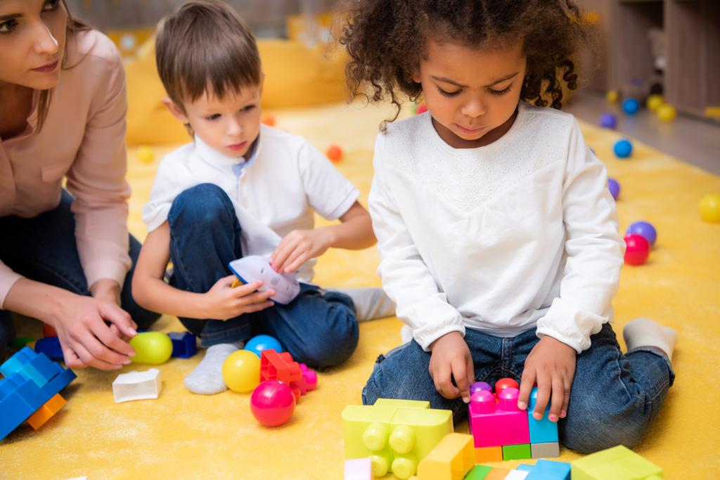 засмучений афро-американських дитини грати з кольоровими конструктор в дитячому садку - Фото, зображення