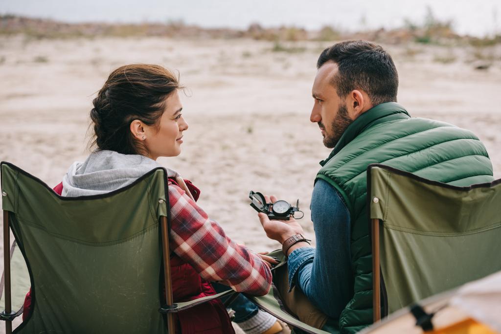 back view of couple with compass resting on chairs while having camping - Photo, Image