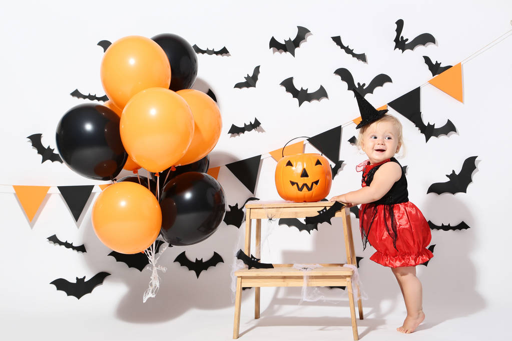 Holčička v halloween kostýmu s balónky a dýňová kbelík na bílém pozadí - Fotografie, Obrázek