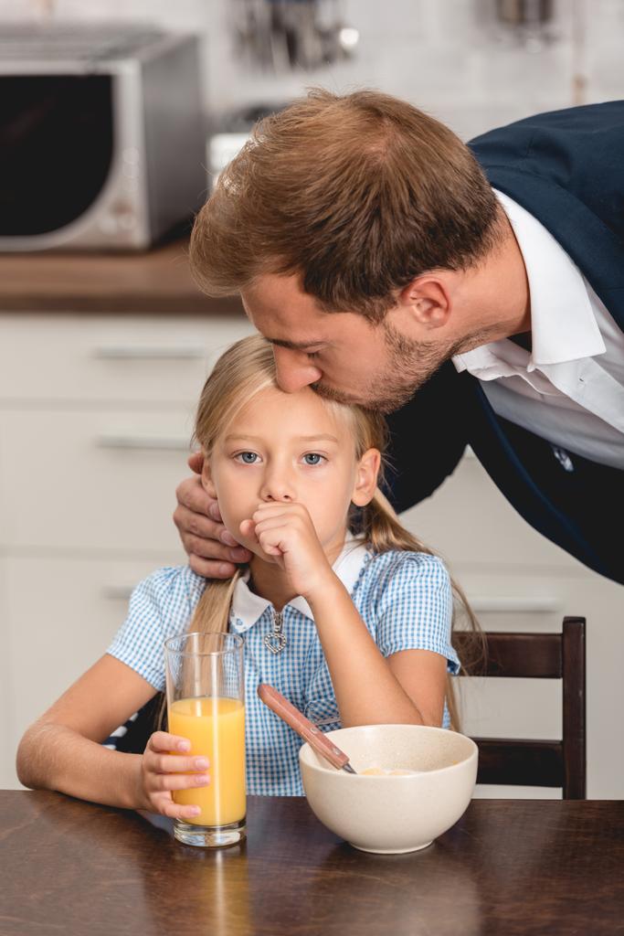 jonge vader controle van temperatuur van zieke dochter met lippen tijdens het ontbijt - Foto, afbeelding