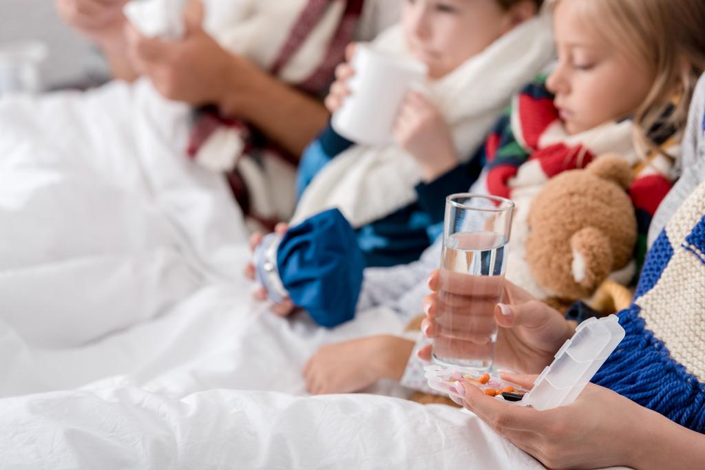 περικοπεί βολή του άρρωστος νεαρή οικογένεια κάθεται στο κρεβάτι μαζί - Φωτογραφία, εικόνα