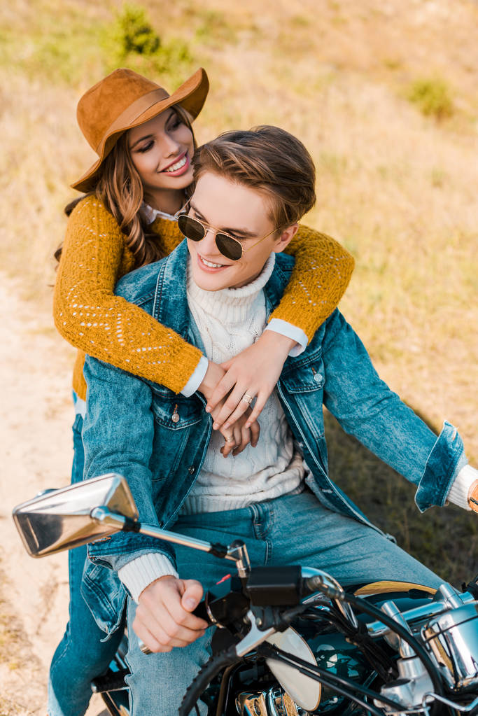 joven novia abrazando novio sentado en vintage moto en prado
  - Foto, imagen
