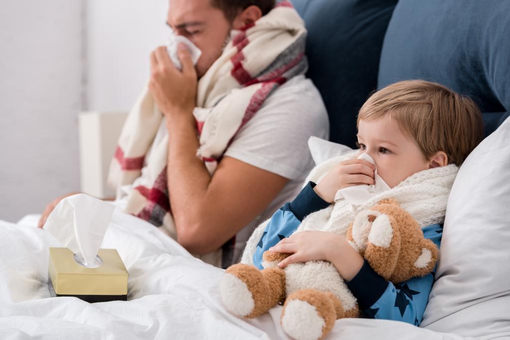 malato padre e figlio soffia nasi con tovaglioli di carta mentre sdraiato a letto
 - Foto, immagini