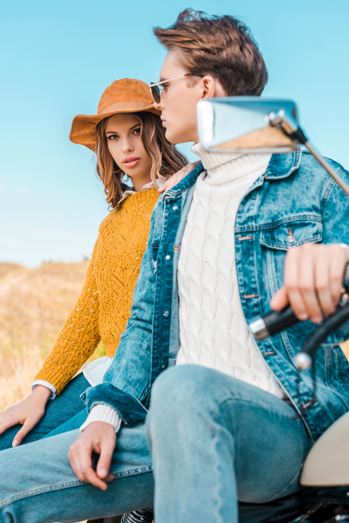 atractiva pareja sentada en moto retro en prado rural
 - Foto, Imagen