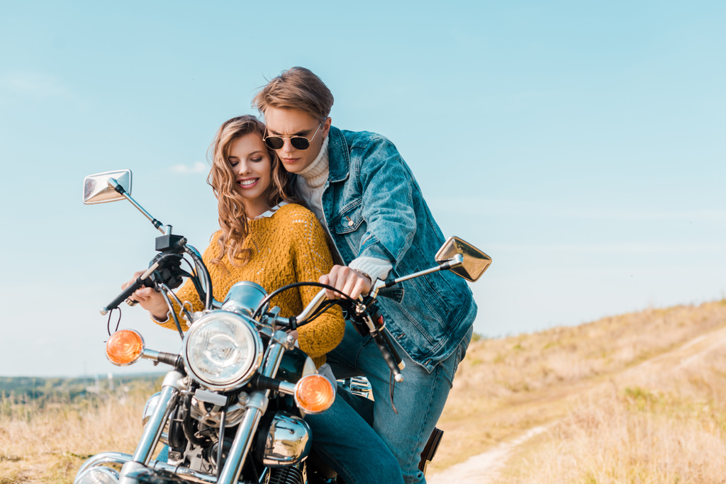 田舎の牧草地のビンテージ バイクで探している若いカップル - 写真・画像