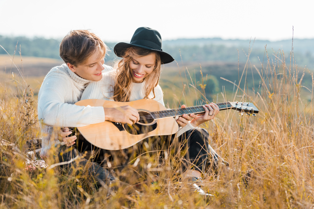 happy couple playing guitar on rural meadow - Photo, Image