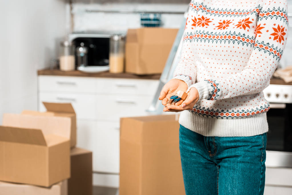 обрізане зображення жінки, що тримає ключі на кухні з картонними коробками в новому будинку
 - Фото, зображення