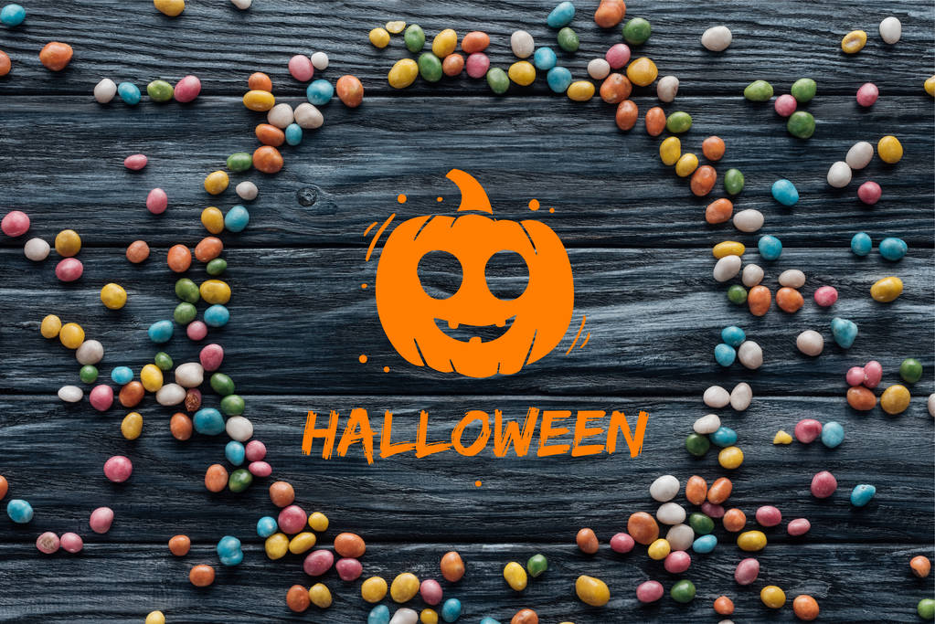 Kreis aus bunten leckeren Bonbons auf Holzgrund mit Kürbis und "halloween" -Schriftzug - Foto, Bild