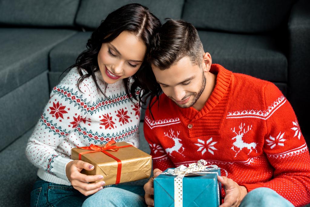 Selektiver Fokus glücklicher Paare, die mit Weihnachtsgeschenkboxen zu Hause sitzen  - Foto, Bild