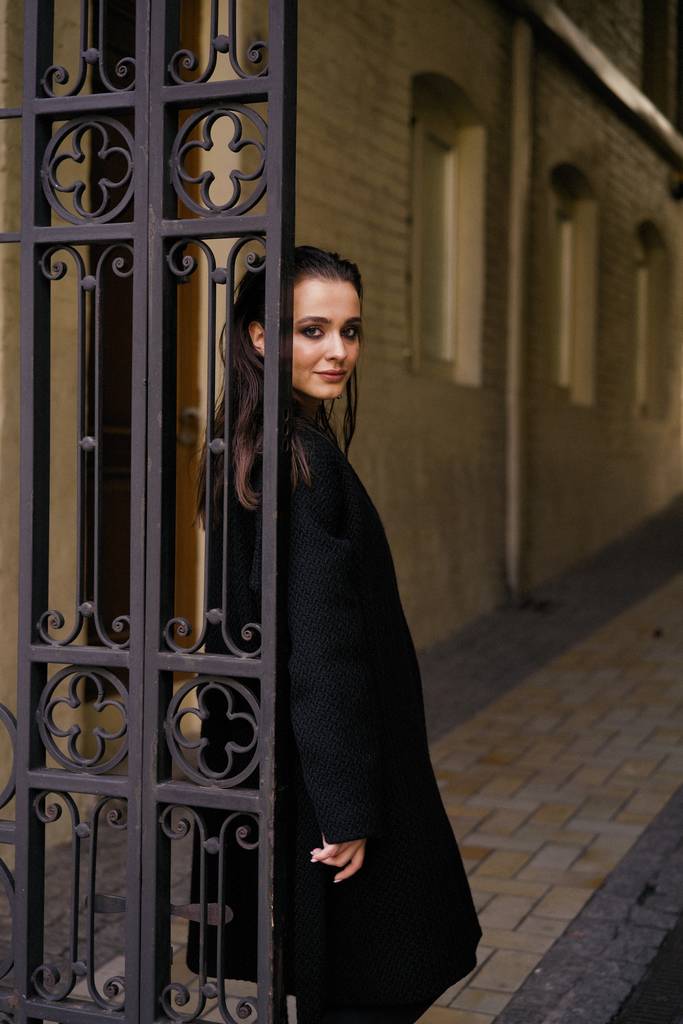 Πανέμορφη μελαχρινή νεαρή γυναίκα με μαύρα ρούχα που παρουσιάζουν - Φωτογραφία, εικόνα