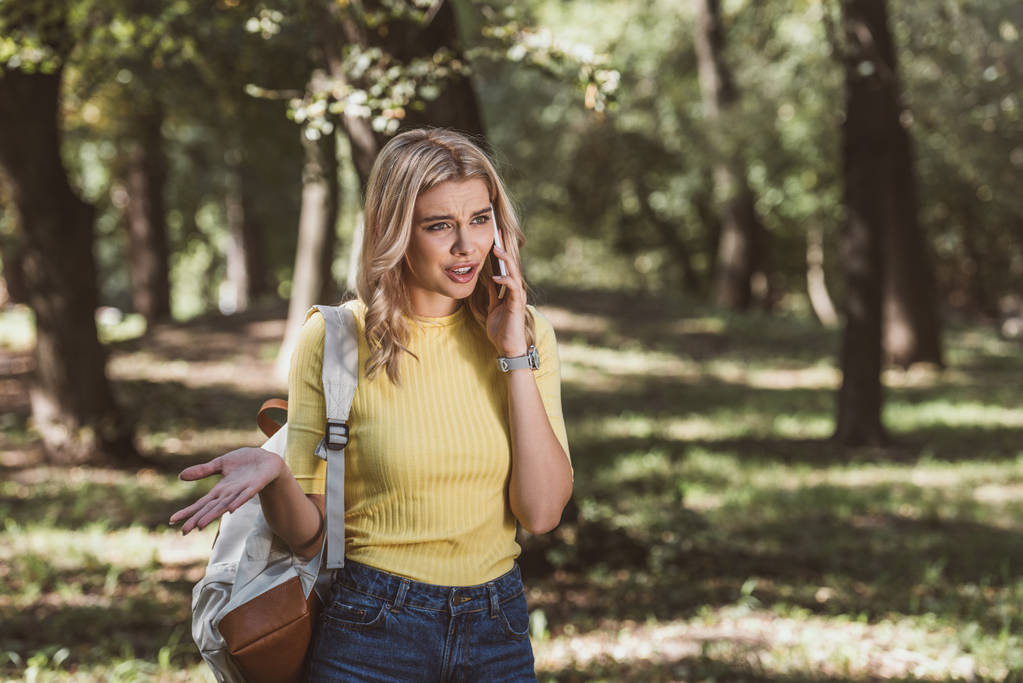 portrait de jeune femme émotionnelle avec sac à dos parlant sur smartphone dans le parc
 - Photo, image