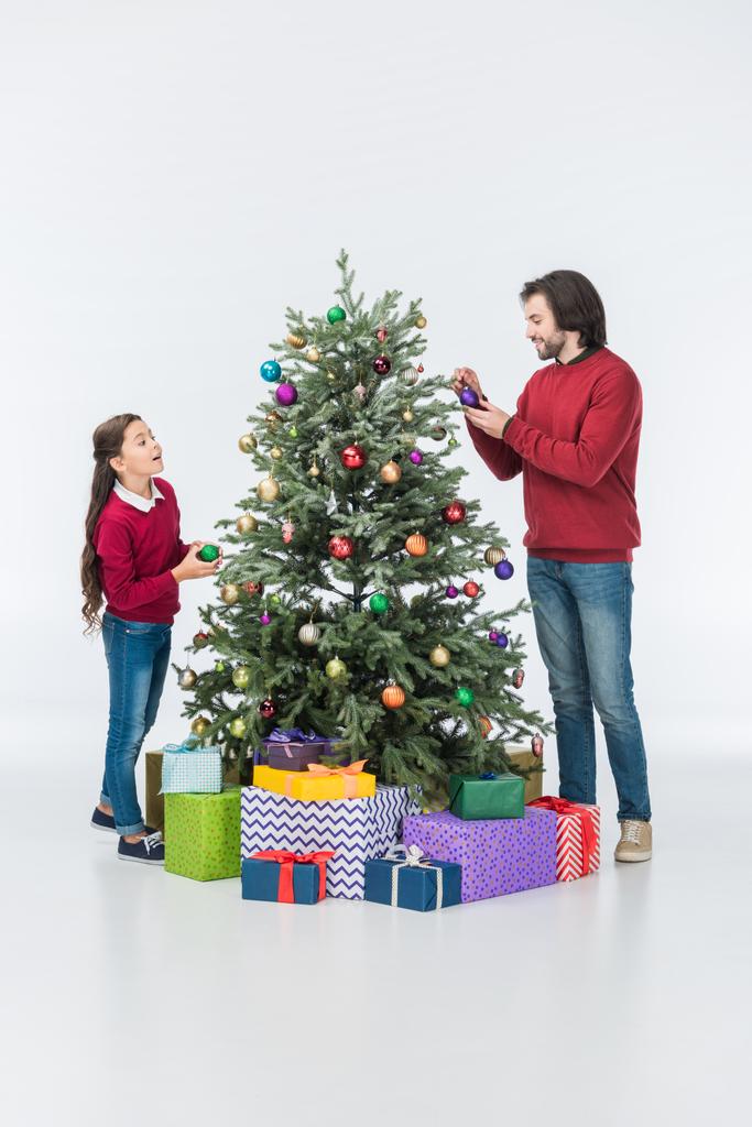 usmíval se otec s dcerou zdobení vánočního stromu s skleněné kuličky izolované na bílém - Fotografie, Obrázek