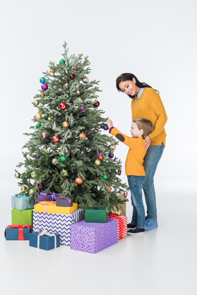 mother with son decorating christmas tree with presents isolated on white - Photo, Image