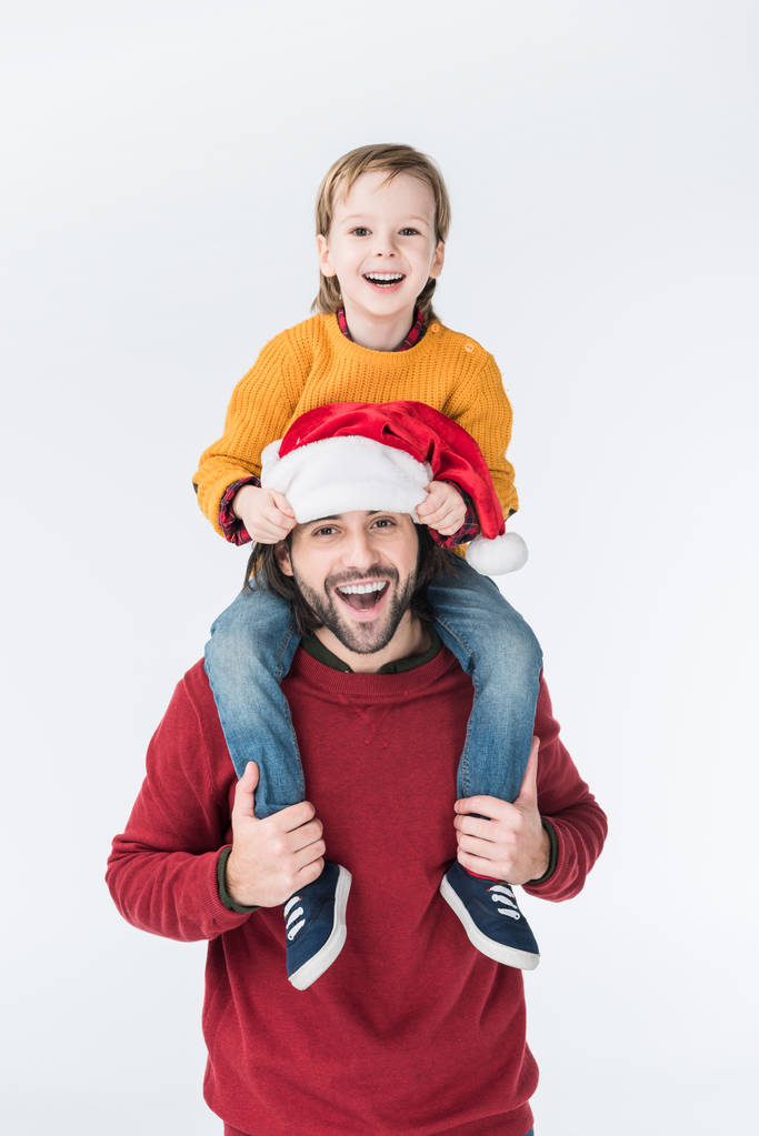 smiling father in santa hat carrying son on shoulders isolated on white - Photo, Image