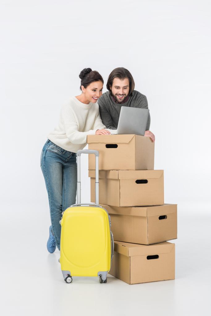 happy couple using laptop on cardboard boxes isolated on white - Photo, Image