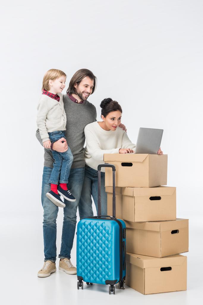 glückliche Familie mit Laptop auf Kartons isoliert auf weiß - Foto, Bild