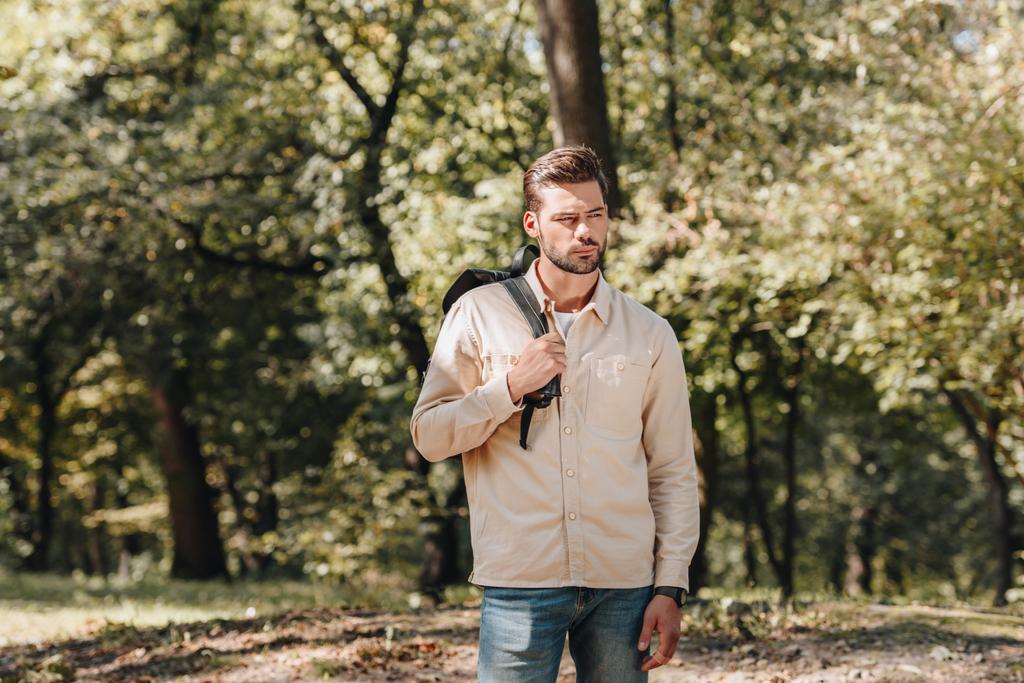 töprengő fiatalember backpack állandó őszi parkban portréja - Fotó, kép