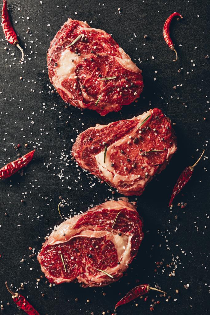 felső kilátás nyers steak és szétszórt fűszerek asztalon, konyhában - Fotó, kép