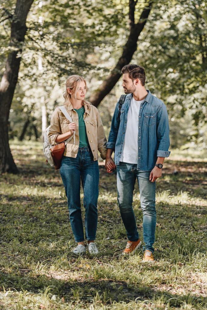 mladý pár stylových podávají ruce během romantické rande v podzimním parku - Fotografie, Obrázek