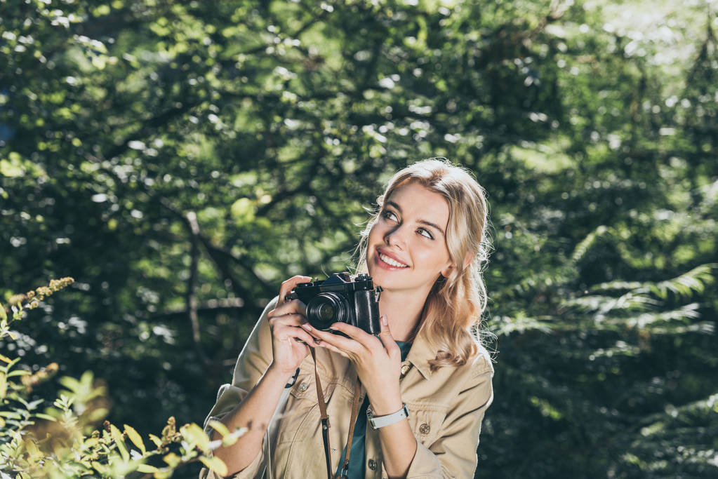Portret van lachende vrouw met fotocamera in park - Foto, afbeelding