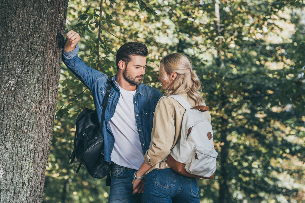 young couple with backpacks looking at each other in park - Photo, Image
