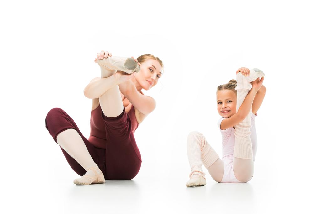 happy little ballerina and her female trainer stretching legs isolated on white background  - Photo, Image