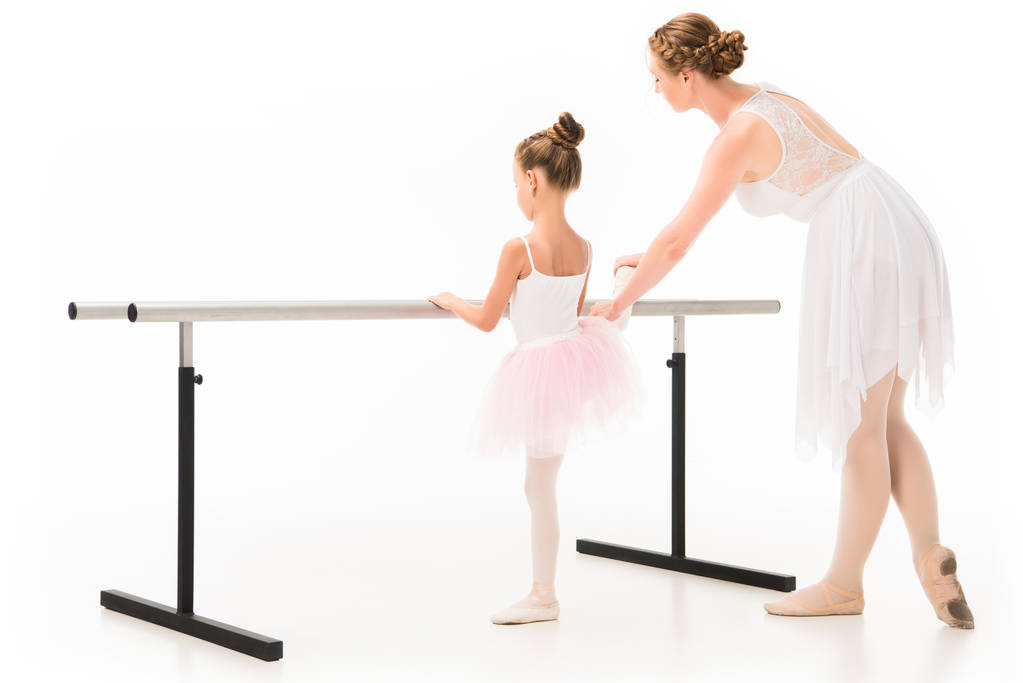 nézet hátulról, segítve a barre balett gyakorló kis balerina tutu-felnőtt női tanár állni a elszigetelt fehér háttér  - Fotó, kép