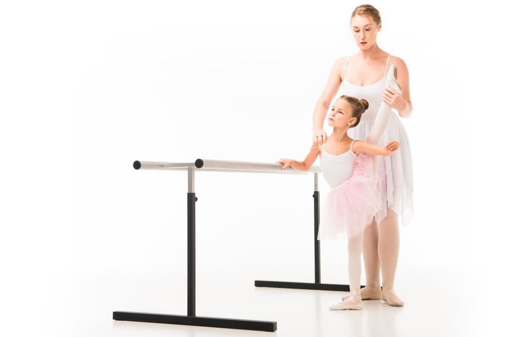 profesora centrada en tutú ayudando a la pequeña bailarina a practicar en el stand de ballet barre aislada sobre fondo blanco
  - Foto, Imagen
