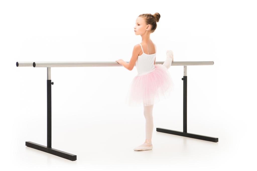 oldalnézetből a kis balerina tutu és a pointe cipők gyakorló balett barre állni elszigetelt fehér background  - Fotó, kép