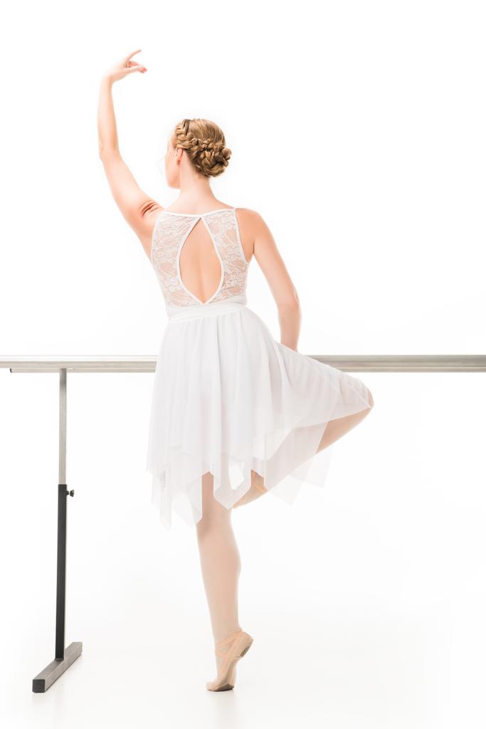 πίσω όψη του μπαλαρίνα σε παπούτσια tutu και pointe εξάσκηση στο περίπτερο barre μπαλέτο που απομονώνονται σε λευκό φόντο  - Φωτογραφία, εικόνα