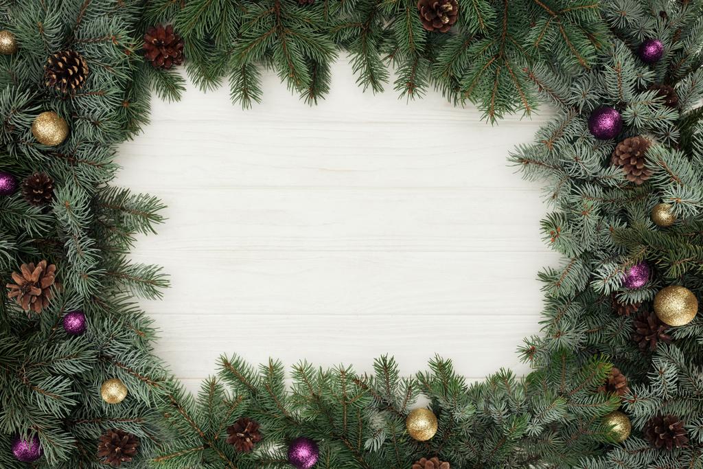 top view of beautiful evergreen fir twigs with shiny baubles and pine cones on white wooden background   - Photo, Image