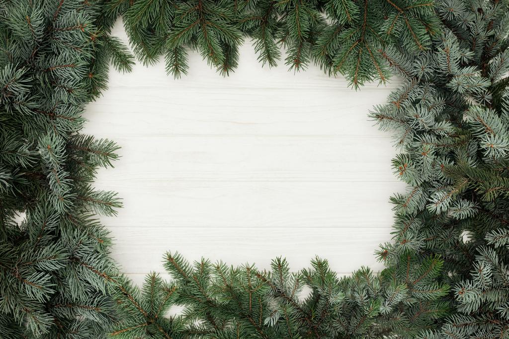 bovenaanzicht van mooie groenblijvende fir twijgen op witte houten achtergrond  - Foto, afbeelding