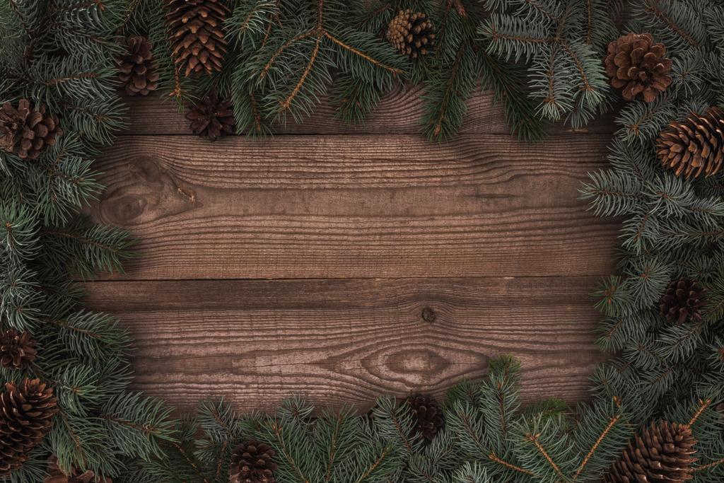 top view of beautiful evergreen coniferous branches and pine cones on wooden background  - Photo, Image