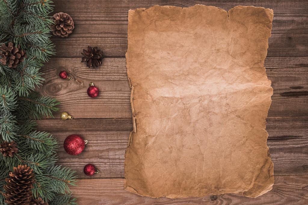 вид сверху на чистый пергамент, хвойные ветви с шишками и безделушками, рождественский фон
 - Фото, изображение