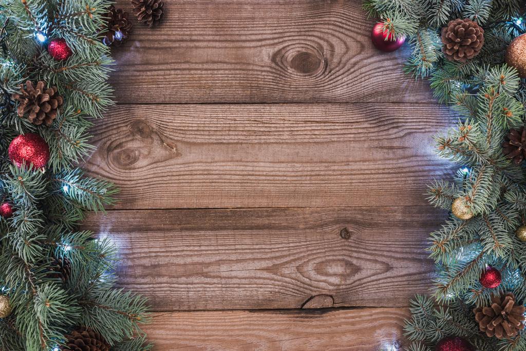 belos galhos de árvore de natal com bugigangas, cones de pinho e guirlanda iluminada em fundo de madeira
  - Foto, Imagem