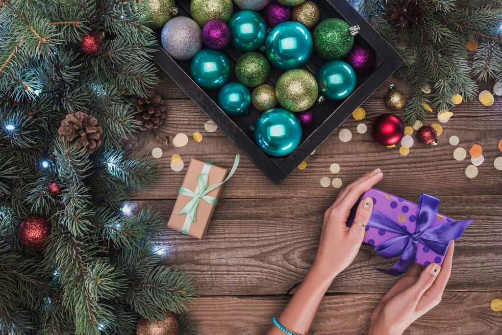 colpo ritagliato di Natale presente nelle mani, bagattelle lucenti e bellissimi ramoscelli di abete con pigne
 - Foto, immagini