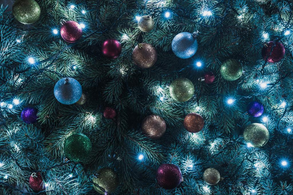 γκρο πλαν θέα όμορφο χριστουγεννιάτικο δέντρο με πολύχρωμες μπάλες και φωτιζόμενο γιρλάντα   - Φωτογραφία, εικόνα