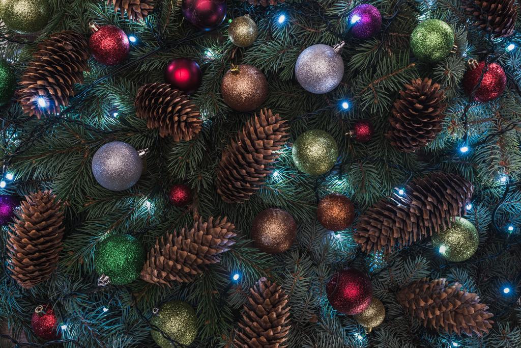 Detailní pohled na krásné vánoční strom s šišky, barevné koule a osvětlené věnec  - Fotografie, Obrázek