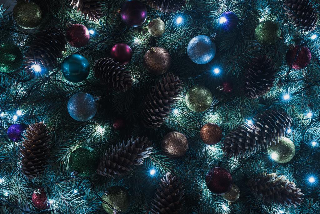vue rapprochée du magnifique sapin de Noël avec des cônes de pin, des boules colorées et des guirlandes illuminées
  - Photo, image