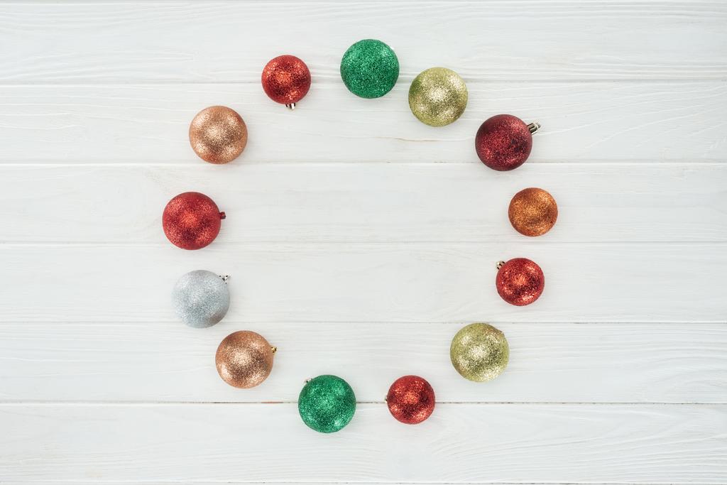 round frame made of beautiful colorful christmas balls on white wooden surface  - Photo, Image