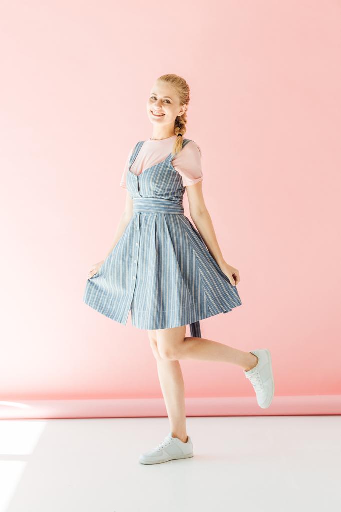 happy young woman in blue dress looking at camera on pink - Photo, Image