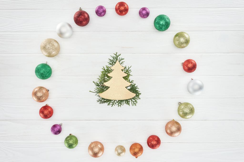 Κάτοψη των κωνοφόρων κλαδιά, χριστουγεννιάτικο δέντρο σύμβολο και πολύχρωμο λαμπερά στολίδια σε ξύλινη επιφάνεια - Φωτογραφία, εικόνα