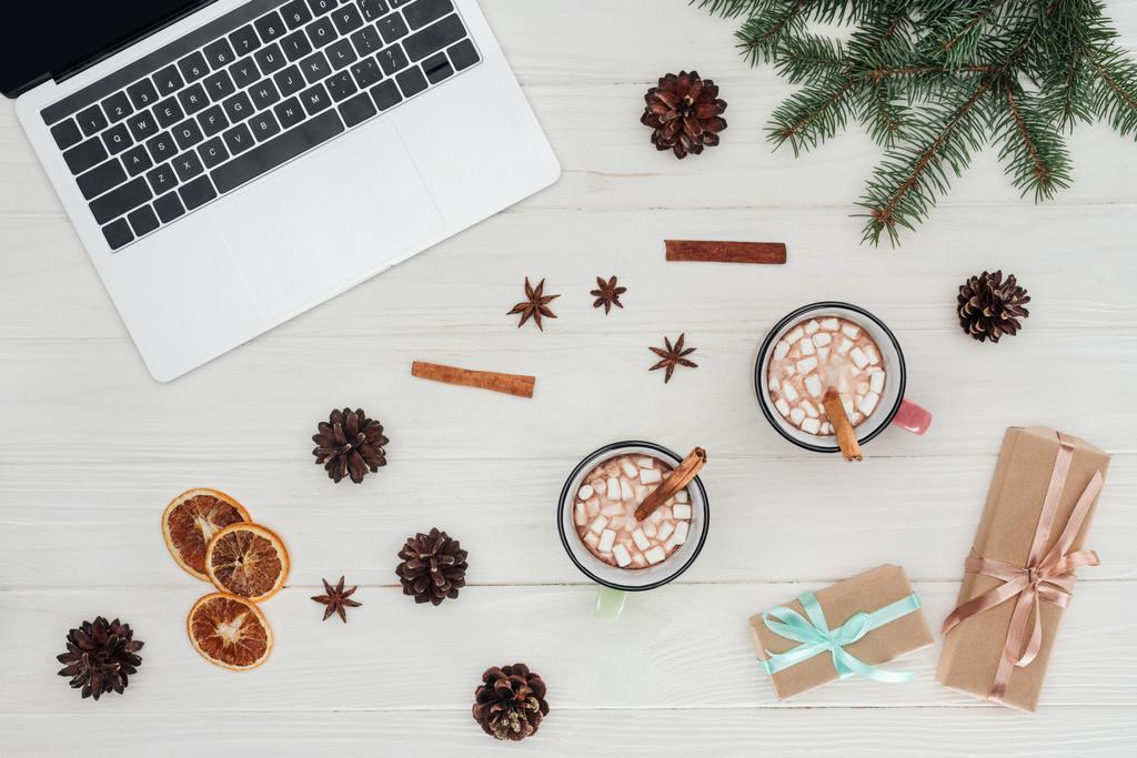 flat lay with laptop, cups of hot chocolate and christmas presents on wooden table  - Photo, Image