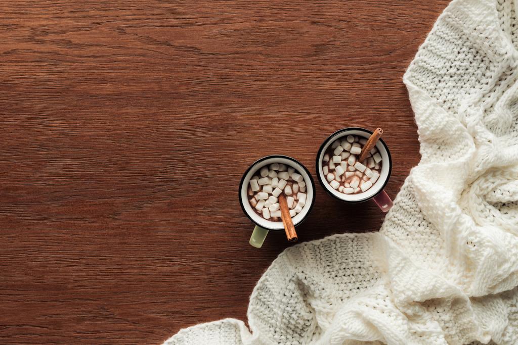 vista superior de tazas con delicioso chocolate caliente, malvaviscos y palitos de canela sobre fondo de madera
   - Foto, Imagen
