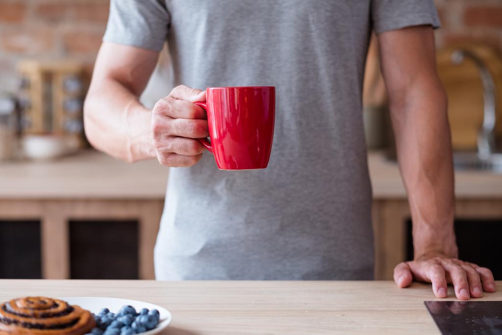 ochtend thee koffie slecht ontbijt gewoonte man rode mok - Foto, afbeelding