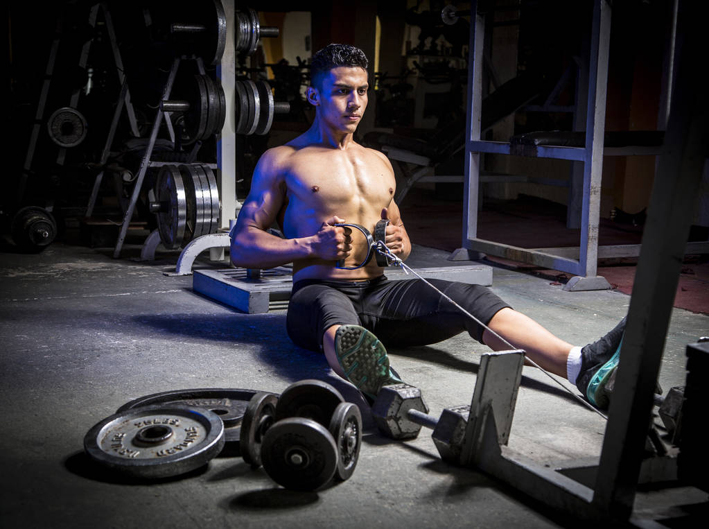 Молодий м'язистий чоловік у спортзалі займається фізичними вправами. Показує м'язи
. - Фото, зображення