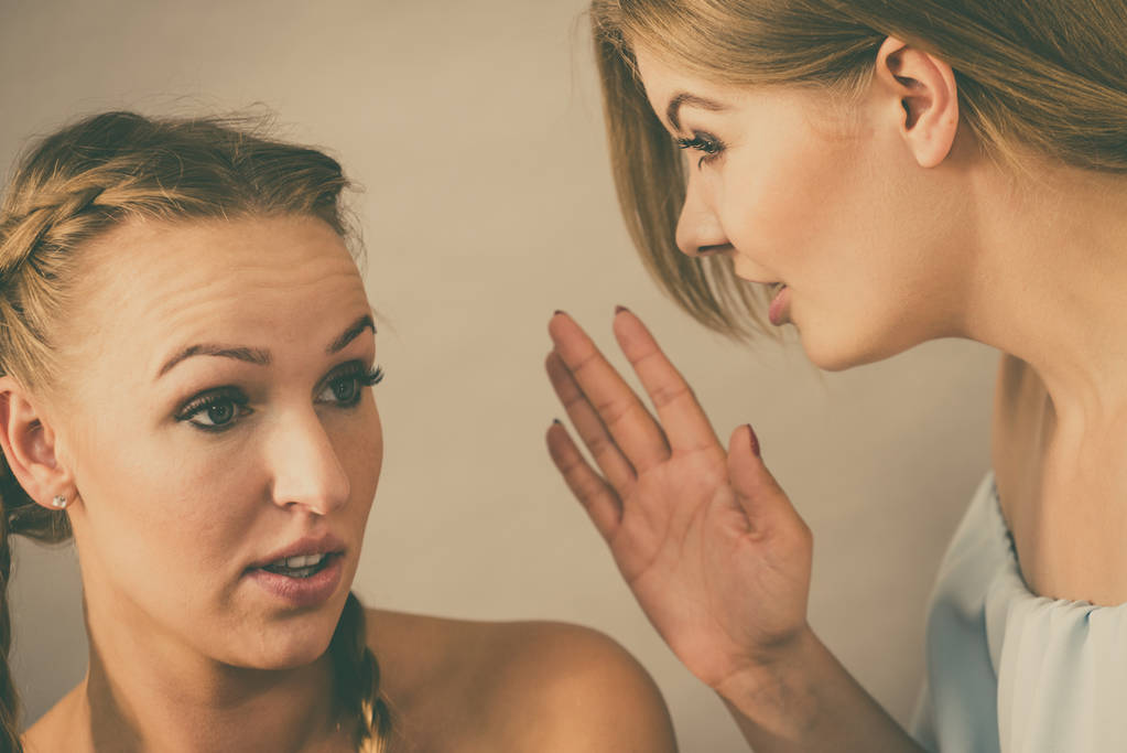 Mujer joven contándole a su amiga algunos secretos, dos mujeres hablando chismes. Emocionada chica emocional susurrando al oído - Foto, imagen
