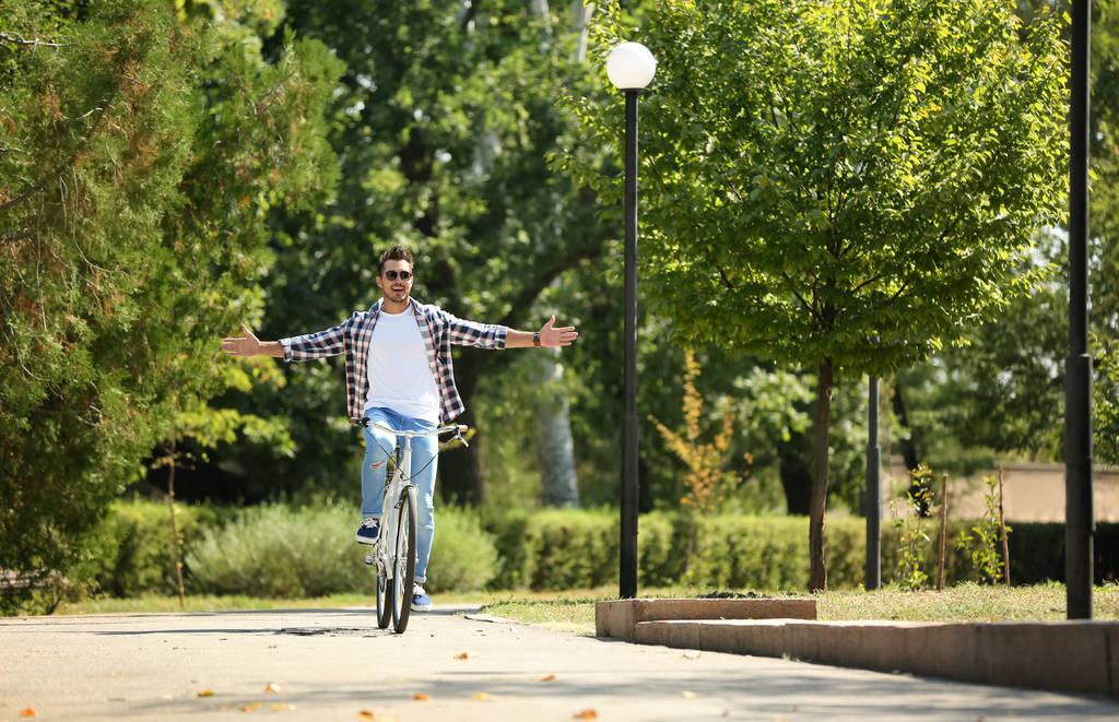 schöner junger Hipster-Mann fährt Fahrrad im Park - Foto, Bild