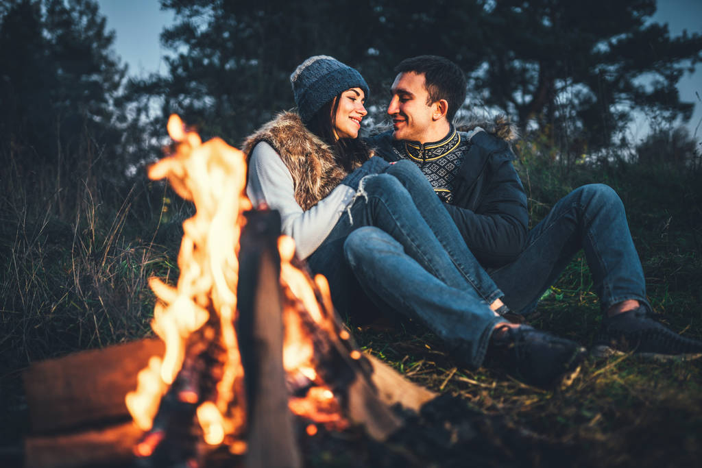 Krásná mladá dvojice relaxační u ohně v lese na večerní čas - Fotografie, Obrázek