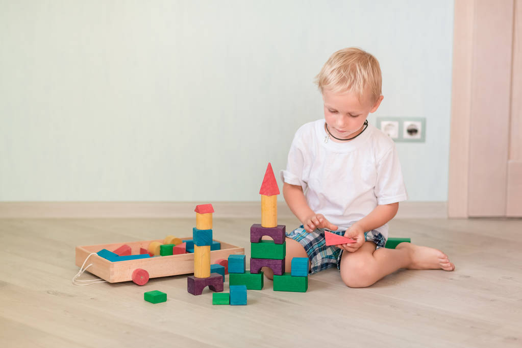 Sevimli küçük çocuk odasında renkli tahta bloklarla oynama. Erken geliştirme kavramı - Fotoğraf, Görsel